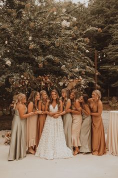 a group of women standing next to each other in front of a lush green tree