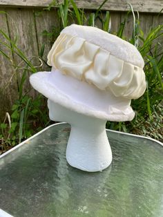 "This is an original 1940s-1950s faux fur cloche hat, milliner unknown. It features a gathered white satin ribbon around its crown, atop a broad white grosgrain ribbon all around (see images). This would have been appropriate wear for most any formal occasion (like weddings), but also many informal occasions, such as garden parties, worship services, pointing to the accused from the witness stand, etc. The circumference on the inside is 22 inches, which equates to (of course) a USA women's size 22 or a size 7 (if that sizing scale is more familiar to you). The depth of the hat is 5.5\" from brim to crown, and it is meant to encircle the head, not simply lie atop it. That said, if the wearer has a great deal of hair to pile up inside, a hat pin might help to secure it in place. There is a l Cream Cloche Hat For Evening, Vintage Cream Cloche Hat For Party, Vintage Cream Mini Hat For Formal Events, Vintage Cream Mini Hat For Formal Occasions, White Fitted Cloche Hat For Formal Occasions, Vintage White Cloche Hat, Vintage White Mini Hats For Evening, White Vintage Mini Hats For Evening, Vintage White Costume Hat With Short Brim