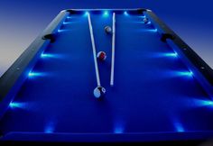 a pool table with blue lights on the top and two white sticks sticking out of it