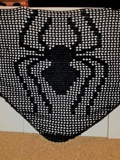 a black and white crocheted rug on the floor in front of a tiled wall