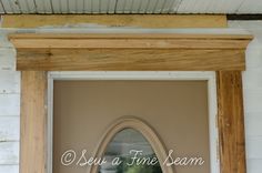 an arched wooden mirror hanging on the side of a building