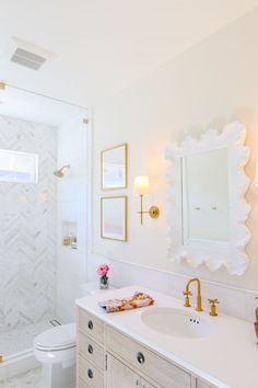 a white bathroom with gold accents and marble counter tops