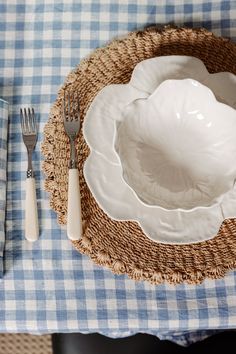 a blue and white checkered table cloth with silverware in a basket on it