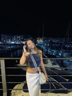 a woman standing on top of a boat holding a cell phone to her ear and smiling at the camera