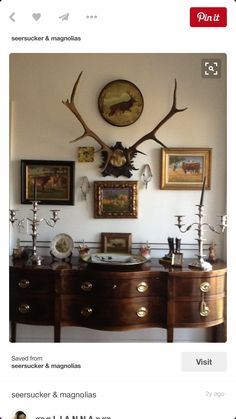 a wall with deer antlers on it and pictures hanging above the dressers in front of them