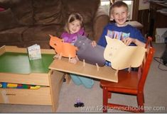 two children sitting on the floor holding up paper animals