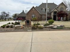 two people are standing in front of a large house with landscaping on the side walk