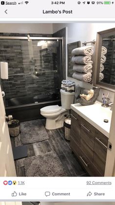 a bathroom with gray tile and wooden cabinets, toilet, sink, and shower stall