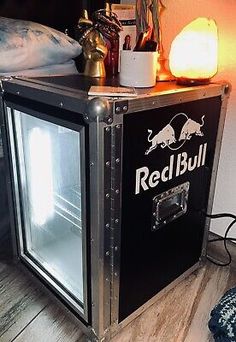 a red bull mini fridge sitting on top of a wooden floor next to a lamp