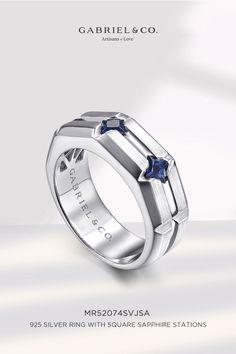 a white gold ring with two blue sapphire stones on the side and an inscription that reads,