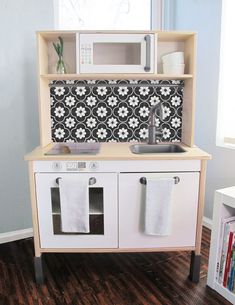 a toy kitchen with sink, microwave and cabinets