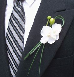 a man wearing a suit and tie with flowers on it's lapel pin