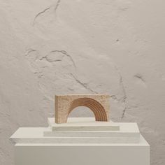 a sculpture on top of a white pedestal in front of a wall with a small arch