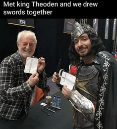 two men standing next to each other in front of a table with paper on it