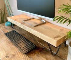 a computer keyboard sitting on top of a wooden desk next to a monitor and potted plant