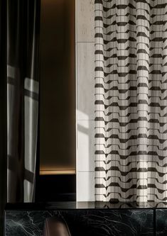 a chair sitting in front of a window next to a black and white tile wall