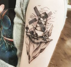 a woman's arm with a windmill tattoo on it