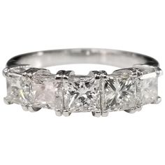 a three stone diamond ring with four princess cut diamonds on the sides and side stones