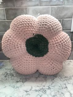 a pink flower shaped object sitting on top of a marble counter next to a brick wall