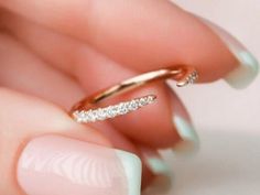 a woman's hand holding a gold ring with white diamonds on the inside of it