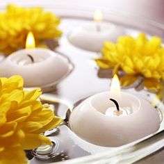 yellow flowers floating in water with candles