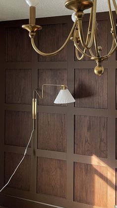 a chandelier hanging from the ceiling in front of a wooden paneled wall