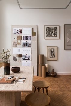 a room with wooden floors and various pictures on the wall, including vases and chairs