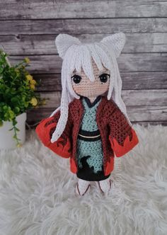 a crocheted doll with white hair wearing a red jacket