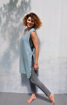 a woman standing in front of a wall with her hands on her hips and smiling