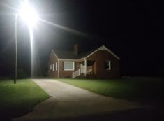 a house is lit up at night with street lights in the front yard and driveway