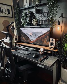 a computer desk with a monitor, keyboard and mouse on it in front of some plants