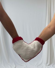 two hands with crocheted mittens holding each other's fingers in the shape of a heart