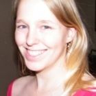 a woman with long blonde hair smiling at the camera while wearing a pink shirt and earrings