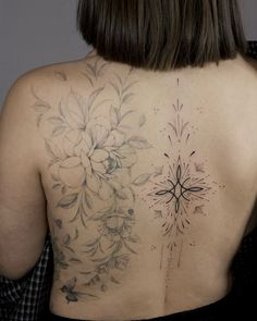 the back of a woman's tattoo with flowers on her upper and lower back