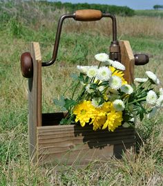 a wooden planter with flowers in it sitting on the side of a grassy field