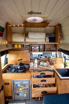 the interior of a camper with drawers, stove and sink in it's center