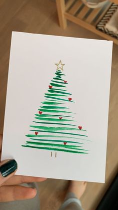 a person holding up a card with a christmas tree drawn on it