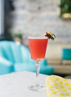 a drink sitting on top of a table next to a blue chair