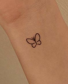 a small tattoo on the wrist of a woman with a butterfly in it's center