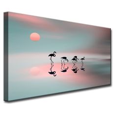 three flamingos walking in the water at sunset with pink and blue sky behind them