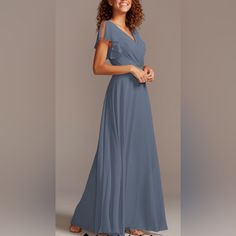 a woman in a long blue dress posing for the camera with her hands on her hips