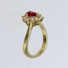 A wonderful cocktail ring by Kurt Wayne.  In 18K yellow gold with a half-twist to the shank. The shank supports a gallery with a central pear-cut ruby and 10 small round cut diamonds.   A high-level ring from the famous New York jewelry designer!  Marked to the shank 750 for 18k gold fineness and with a conjoined KW for Kurt Wayne.  Ring Size: ca. 5 1/2  Dimensions reference the ring size and are not specific to the ring itself. Formal Yellow Gold Ruby Ring With Single Cut Diamonds, Yellow Gold Ruby Ring With Halo Cluster Setting, Red Ruby Ring With Brilliant Pear-shaped Cut, Red Pear-shaped Ruby Ring With Brilliant Cut, Heirloom Yellow Gold Ruby Ring With Halo Design, Heirloom Ruby Ring In Yellow Gold With Halo Design, Pear-shaped Brilliant Cut Yellow Gold Ruby Ring, Pear-shaped Ruby Ring With Center Stone, Red Pear-shaped Ruby Ring With Center Stone