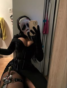 a woman wearing a mask and holding a cell phone up to her face while sitting on the floor