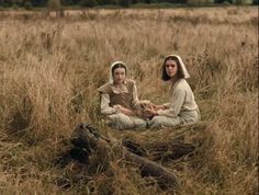 two people sitting in the middle of a field