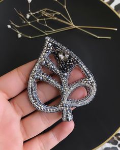 a person is holding a brooch in their hand and it looks like they are wearing a masquerade