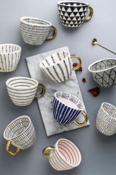 coffee cups and saucers are arranged on a gray surface with gold trimmings