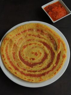 a white plate topped with food next to a bowl of sauce