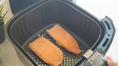 two pieces of fish are being cooked in an air fryer