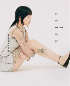 a woman is sitting on the floor with her legs crossed and tattoos on her body