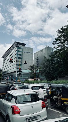 many cars are stopped at an intersection with traffic lights and tall buildings in the background